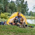 Padre e hijo disfrutando de camping junto a un lago.