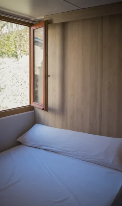 Habitación minimalista con ventana abierta y cama deshecha.